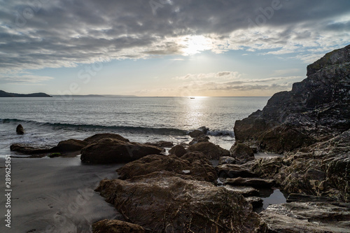 Sonnenaufgang mit Bewölung an felsigem Strand, Südengland