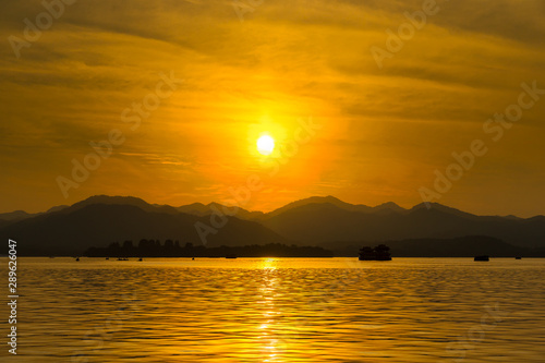 The landscape Background of a golden sunset reflect water and silhouette mountain in west lake (xihu) in Hangzhou CHINA - Image