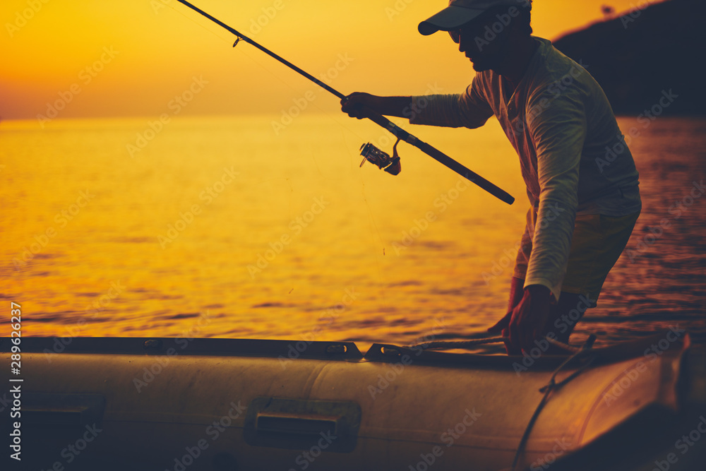 Silhouette of a fisherman fishing in sunset time on the open sea. - obrazy, fototapety, plakaty 