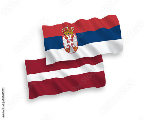National vector fabric wave flags of Latvia and Serbia isolated on white background. 1 to 2 proportion.