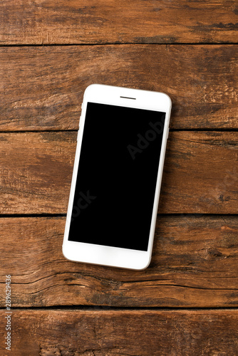 Overhead shot of white smart phone with copyspace on retro wooden background