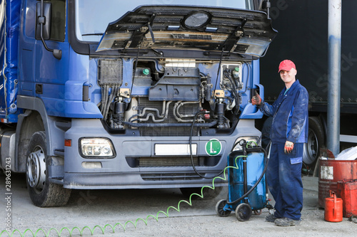 Mechanic repairing truck. Engine oil change. 