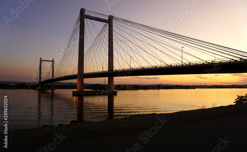 Cable-stayed bridge over river at sunset