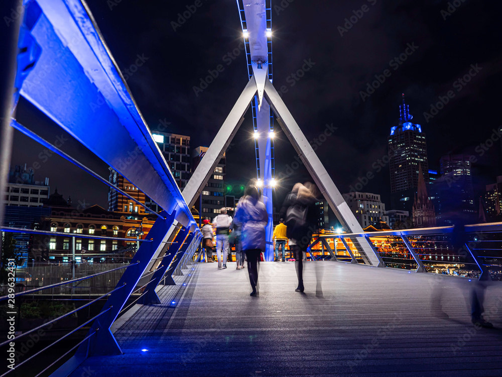 Fototapeta premium Unrecognisable people crossing the bridge over the Yarra river in Melbourne in winter.