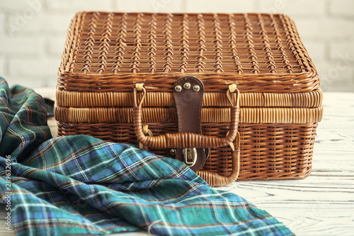 Close up of a wooden basket with dishware on white table