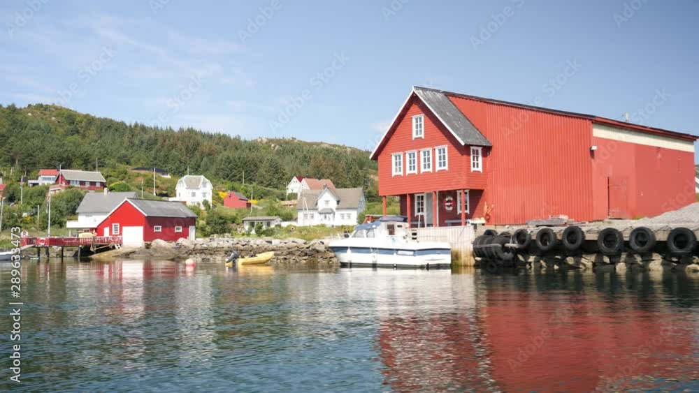 Floating along an inlet and seeing a red boathouse in a picturesque waterfront village Floating along an inlet and seeing a red boathouse in a picturesque waterfront village