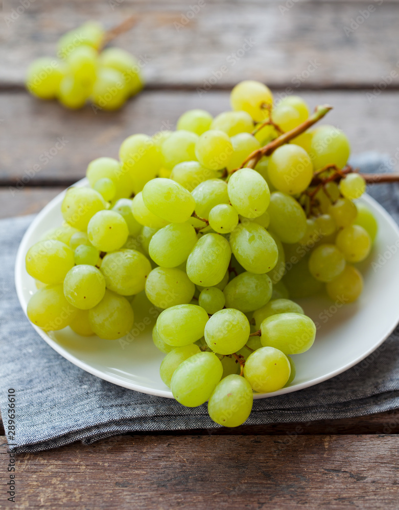 Grape on a white plate. Grey wooden background. Close up. Grape on a white plate. Grey wooden background. Close up.