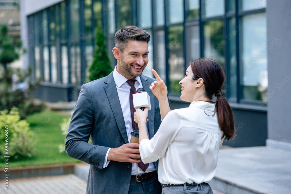 journalist holding microphone and talking with businessman in formal wear - obrazy, fototapety, plakaty 
