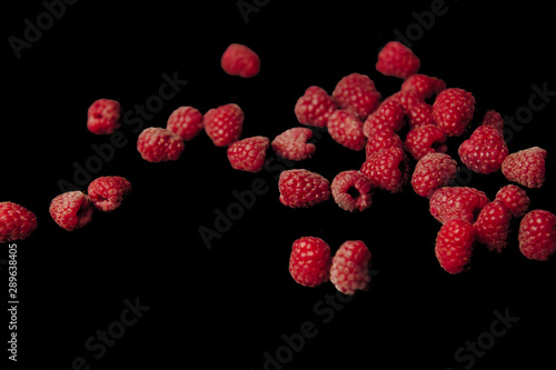 berries of red raspberries in a bunch lie isolated on a black background top view. sweet summer berries