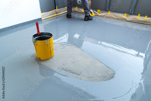 Принти на полотні construction worker renovates balcony floor and spreads watertight resin and glu