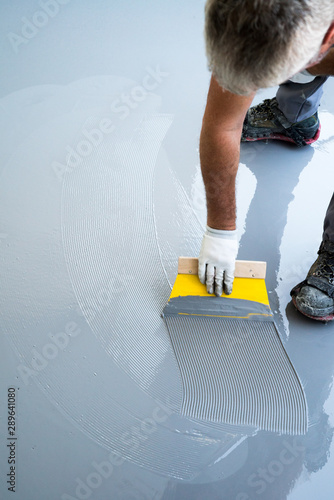 construction worker renovates balcony floor and spreads watertight resin and glue before chipping and sealing