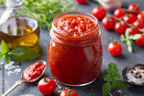 Photos Tomato sauce in a glass jar with fresh herbs, tomatoes and olive oil