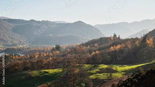 Beautiful Autumn Fall landscape image of the view from Catbells in the Lake District with vibrant Fall colors being hit by the late afternoon sun