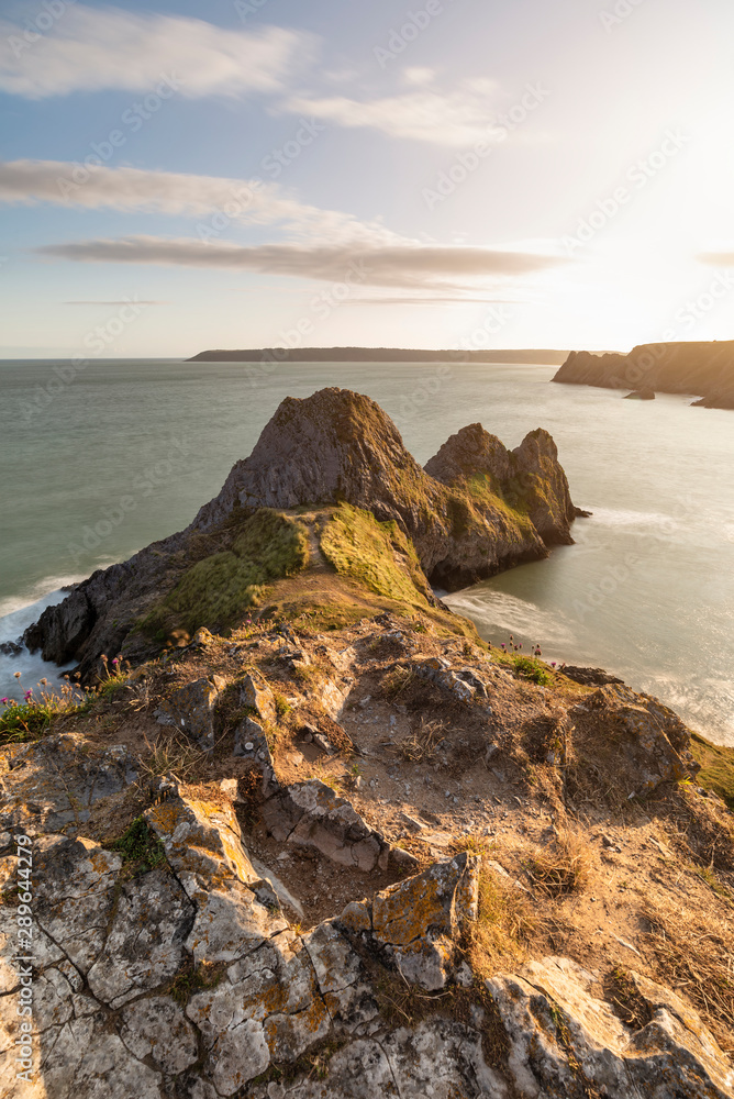 Beautiful peaceful Summer evening sunset beach landscape image at Three Cliffs Bay in South Wales