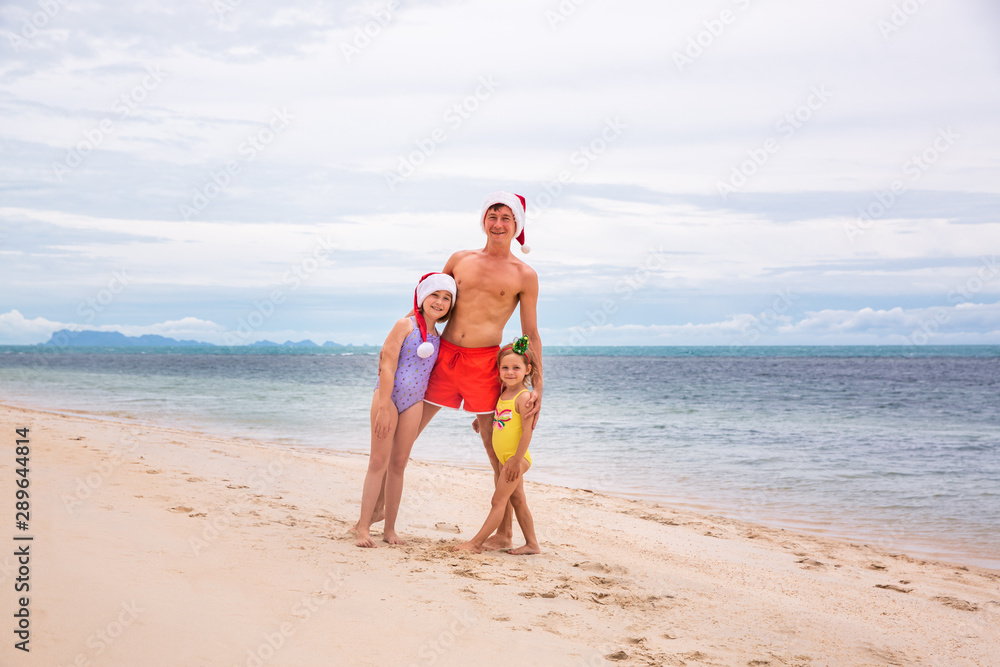 Young friendly family father and two dauthers are happy in summer Christmas on beach Young friendly family father and two dauthers are happy in summer Christmas on beach