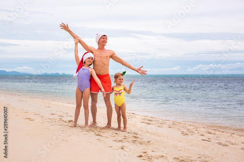 Young friendly family father and two dauthers are happy in summer Christmas on beach