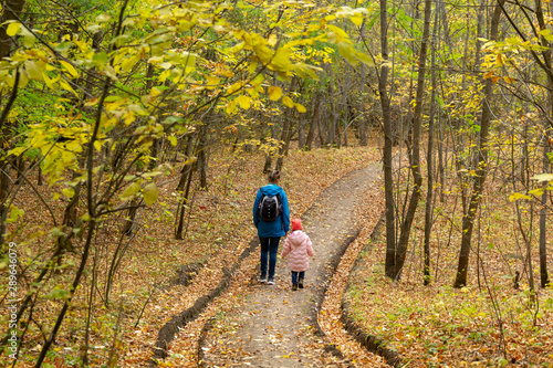 Mother and daughter are walking in the autumn forest © Andrey_Chuzhinov