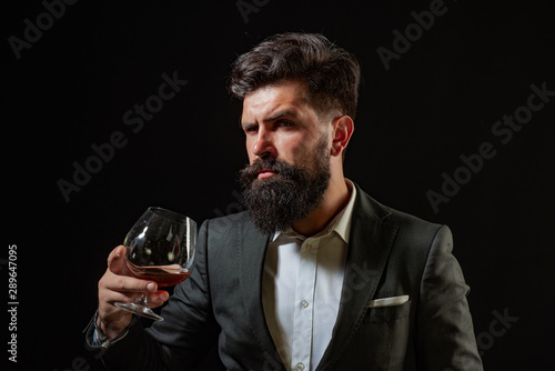 Barman or Bartender serves cognac. Retro vintage man with cognac or scotch. Sommelier man. Confident well-dressed man with glass of cognac.