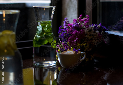 Beautiful glass pitchers with mint, water and fruits. Dishes in the café. Dark background. Cups and glasses.