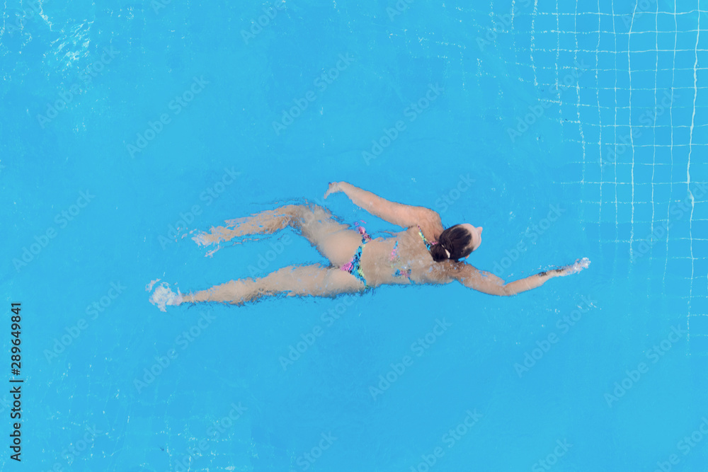 Woman swimming in the pool, top view.