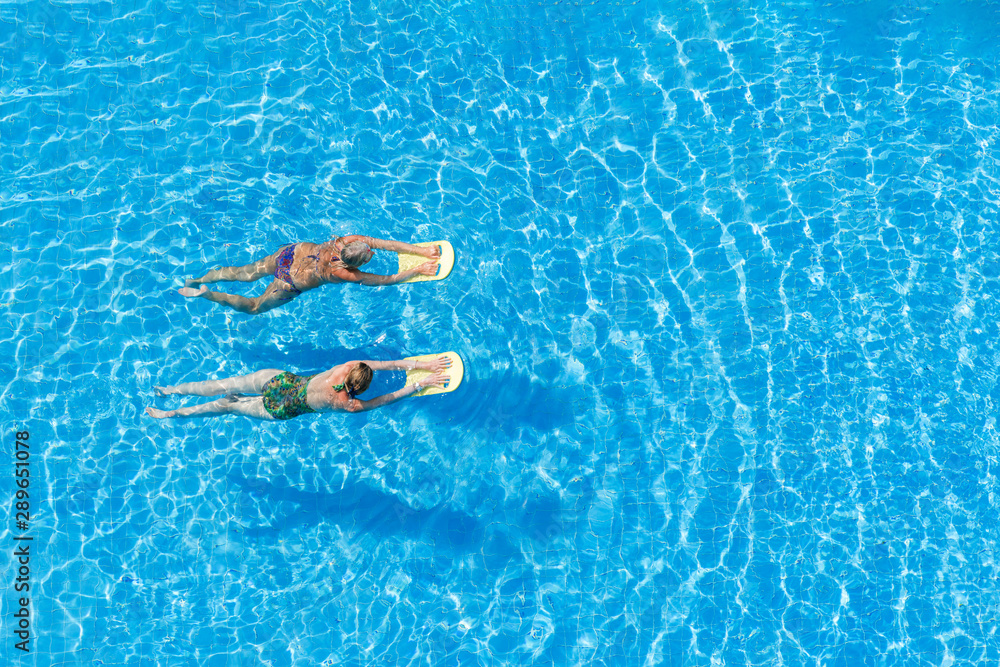 Two women swimming in the pool on a sunny day.