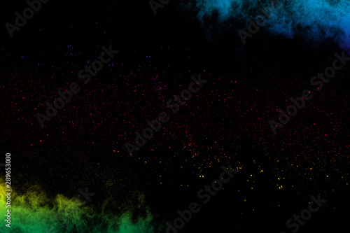 Multi colored powder explosion on black background.Colorful dust splash cloud on dark background.