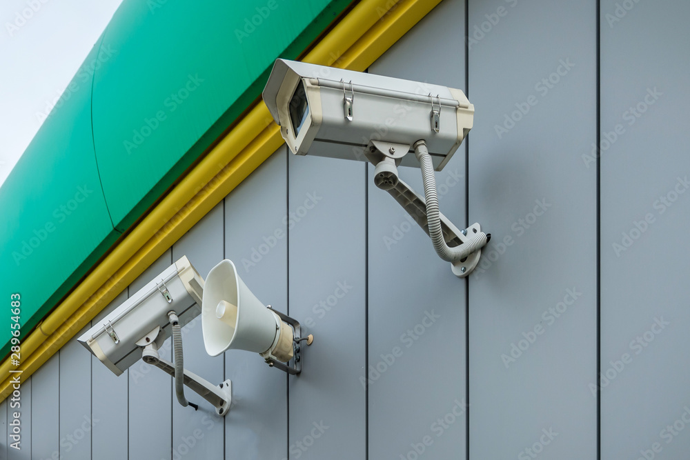 outdoor surveillance and tracking security camera with a megaphone on the wall of building