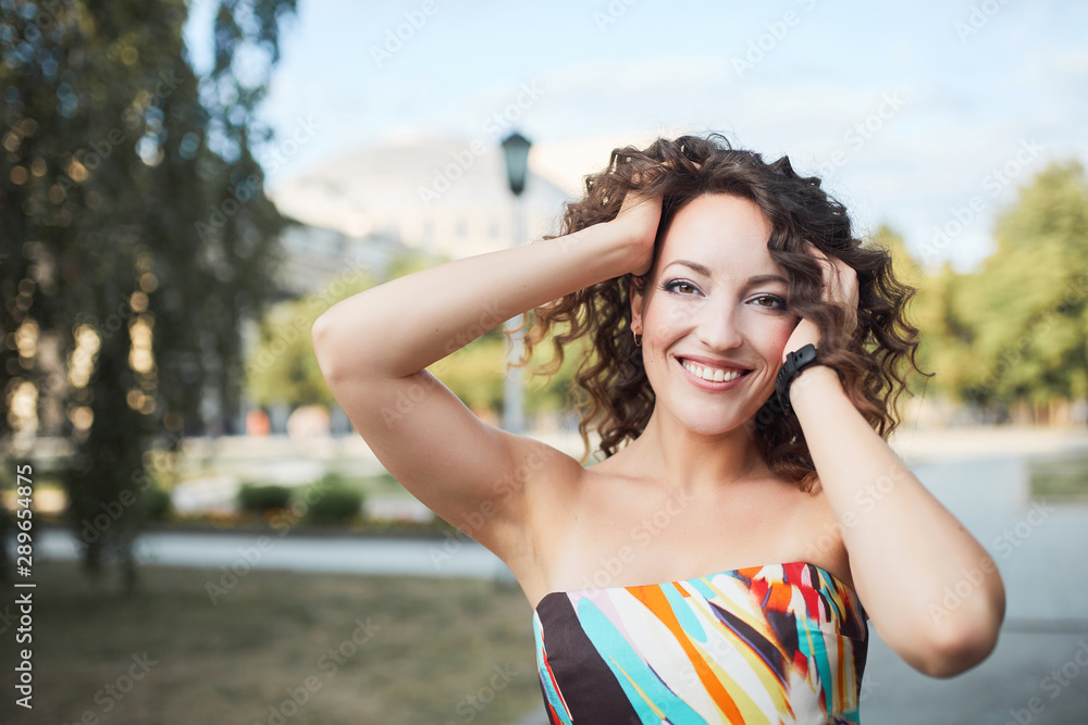 Beautiful brunette girl with hairstyle and make-up walks in the autumn summer park and smiles laughing