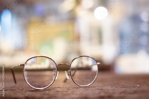 Reading thin frame glasses on wooden table. Vintage style with blur bokeh background.