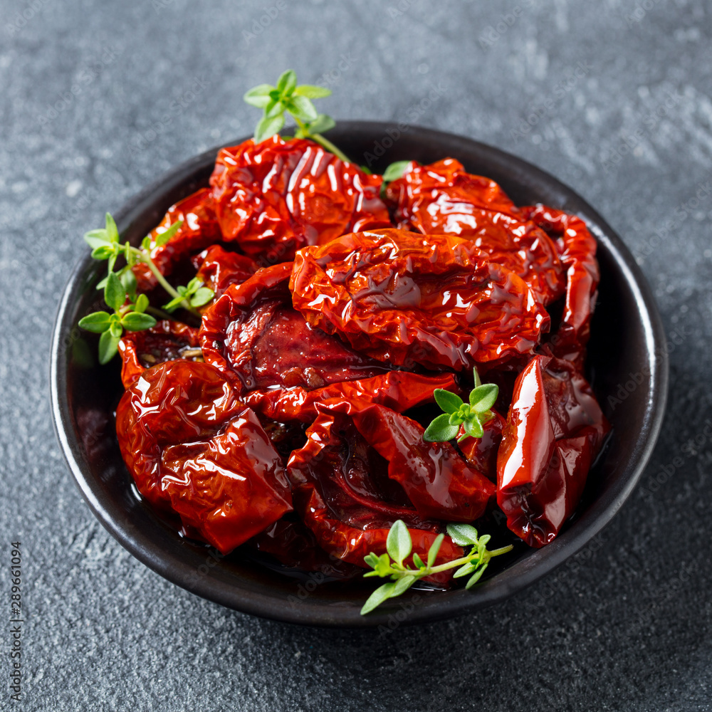 Sun dried tomatoes with fresh herbs and spices. Slate background. Close up. Top view. Sun dried tomatoes with fresh herbs and spices. Slate background. Close up. Top view.