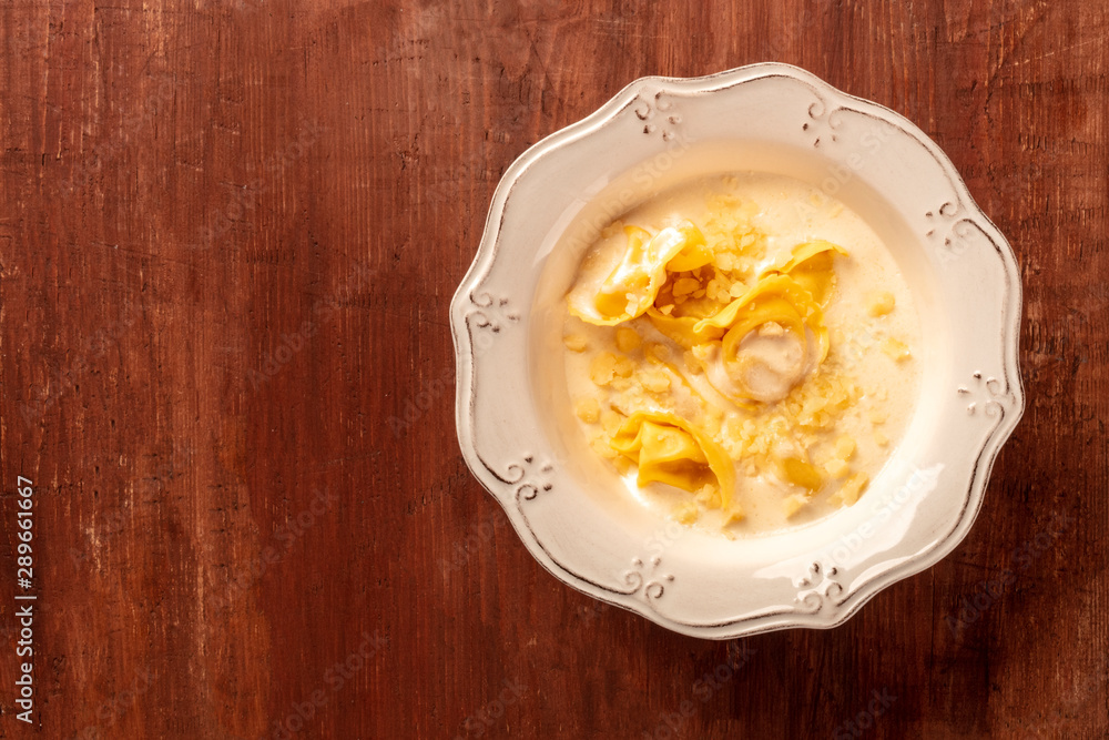 Italian tortellini in a cream sauce with Parmesan cheese, shot from the top on a dark rustic wooden background with a place for text Italian tortellini in a cream sauce with Parmesan cheese, shot from the top on a dark rustic wooden background with a place for text