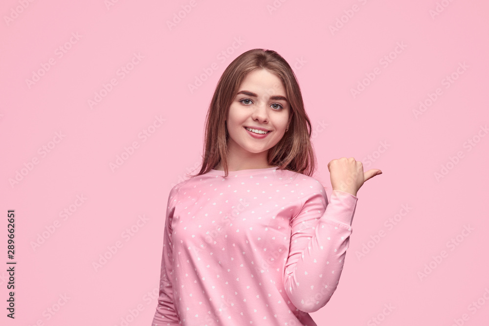 Smiling teen girl in pajama pointing aside Smiling teen girl in pajama pointing aside