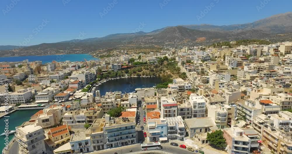 The coastal town of Agios Nikolaos on the island of Crete, during summer. Aerial shot. The coastal town of Agios Nikolaos on the island of Crete, during summer. Aerial shot.