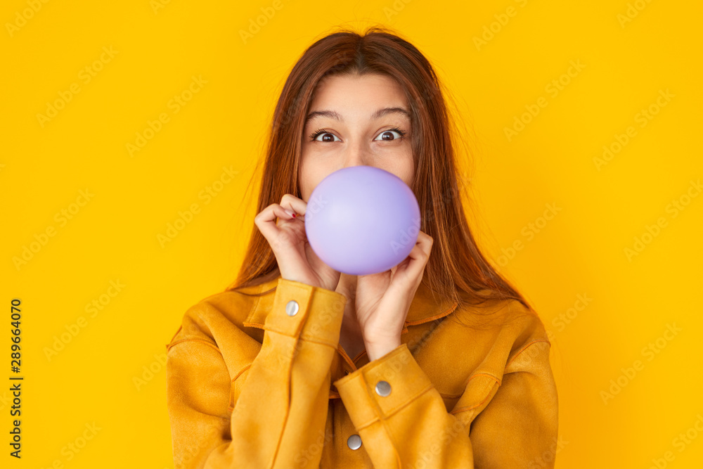 Happy woman blowing balloon and looking at camera Happy woman blowing balloon and looking at camera