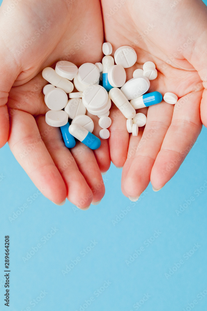 Woman's holding cupped hand full of pills, view from above