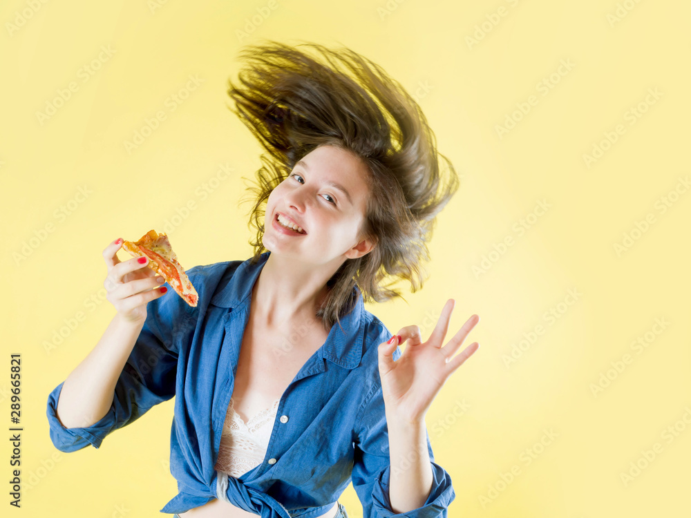 Girl with a piece of pizza in her hands with flying hair on a yellow background Girl with a piece of pizza in her hands with flying hair on a yellow background