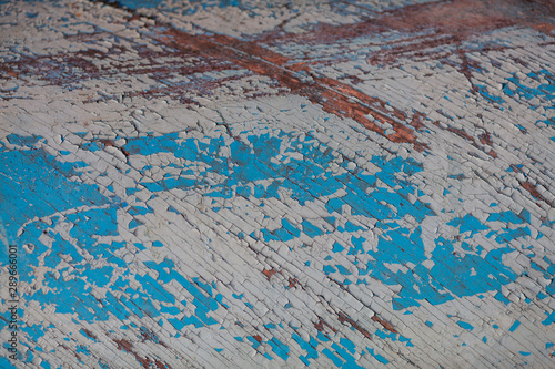 Vintage plywood in blue and white. Weathered paint on a wooden background with cracks.