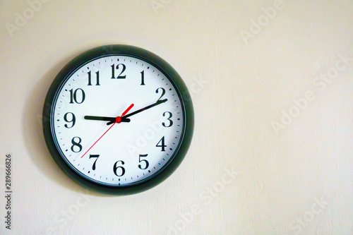 Black clock showing 9.10 o'clock on the wall with Copy Space. Soft focus process.