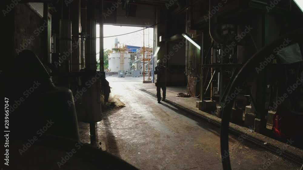 Industrial Engineer wearing safety helmet Walks Through Heavy Industry Manufacturing Factory Industrial Engineer wearing safety helmet Walks Through Heavy Industry Manufacturing Factory