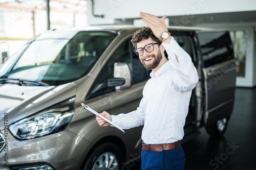 Handsome car dealership worker smiling while standing near the car © F8  \ Suport Ukraine