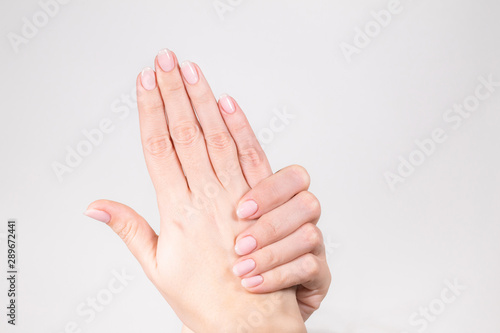 Closeup view of two beautiful female hands isolated on white background. Fingers with fresh pastel nude look manicure at short oval nails. Trend of natural beauty concept. Horizontal color photography