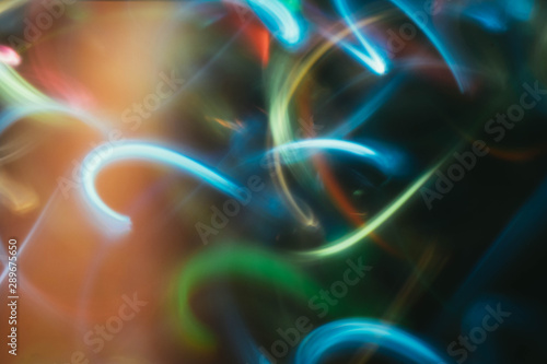 Neon multicolor glowing lines. Defocused gleam in motion. Dark abstract art background.