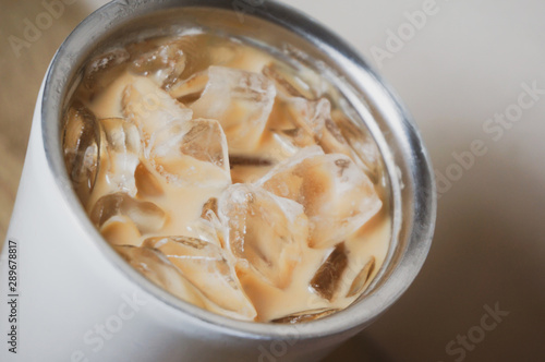 iced coffee and brown plastic straw in white bottle stainless steel cup