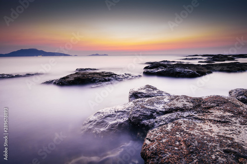 Long exposure landscape photo of sea with rocks during sunset. Milky smooth water. 