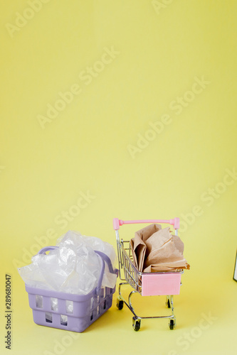 Fototapeta Naklejka Na Ścianę i Meble -  polythene and paper bags in a shopping basket on a yellow background