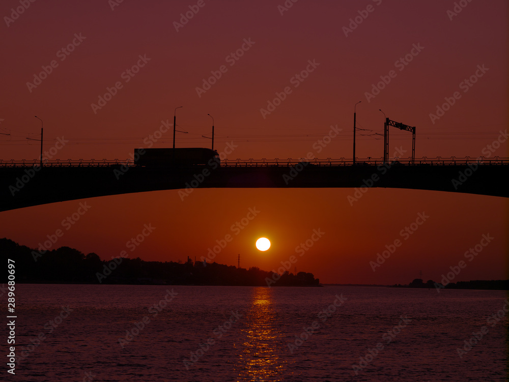 Silhouette of a bridge over water over a river at sunset, cityscape