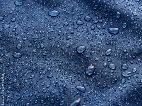 Rain water droplets on blue fiber waterproof fabric. Blue background.