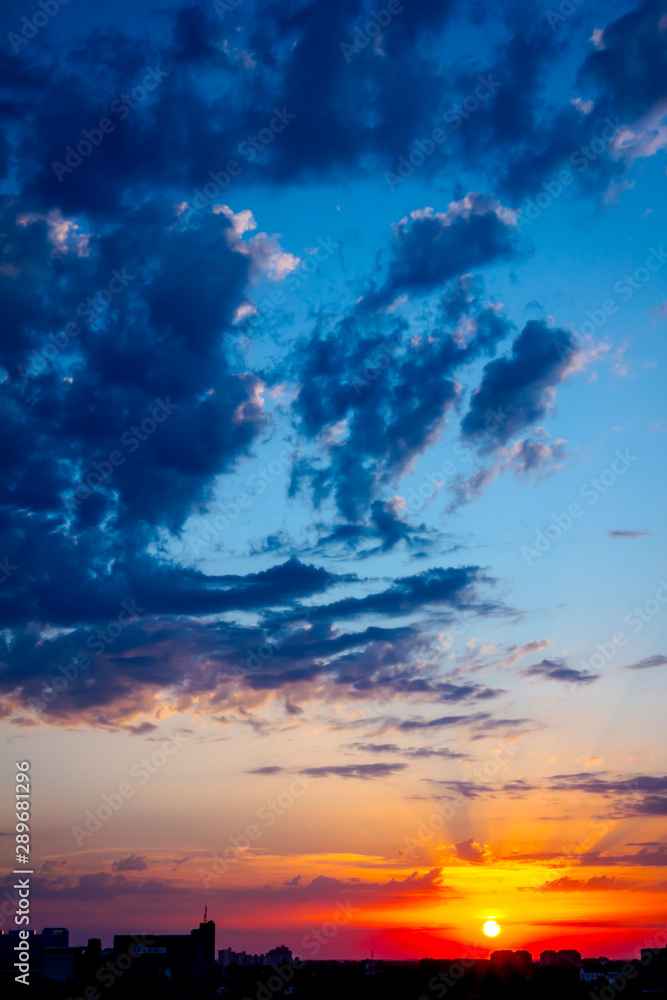 Naklejka premium Blue sky with white clouds at sunset, town in the distance