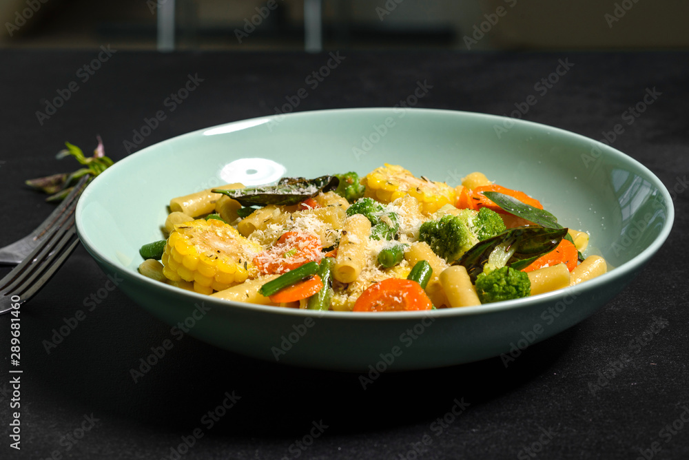 Delicious fresh warm paste sprinkled with cheese parmesan with broccoli, corn, carrots and other vegetables. Vegetarian food Delicious fresh warm paste sprinkled with cheese parmesan with broccoli, corn, carrots and other vegetables. Vegetarian food