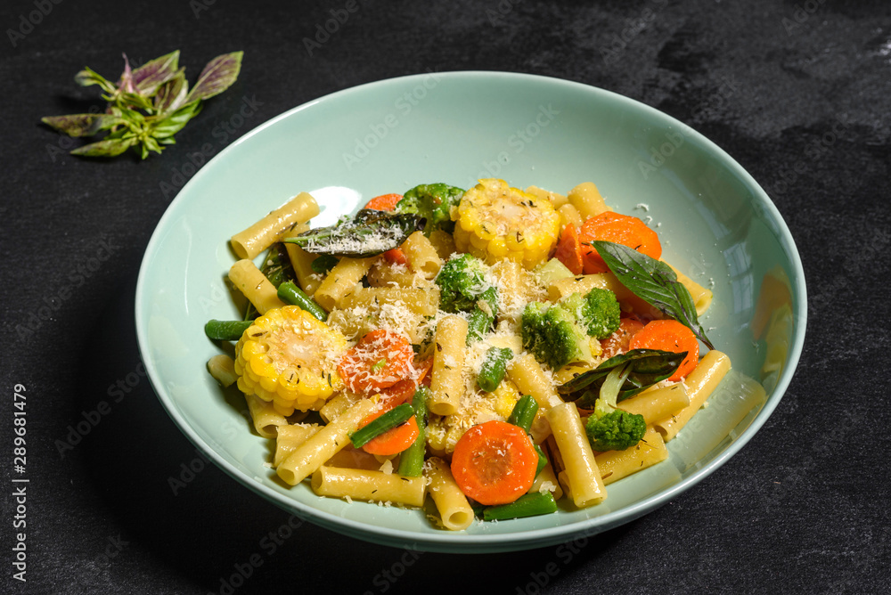 Delicious fresh warm paste sprinkled with cheese parmesan with broccoli, corn, carrots and other vegetables. Vegetarian food Delicious fresh warm paste sprinkled with cheese parmesan with broccoli, corn, carrots and other vegetables. Vegetarian food